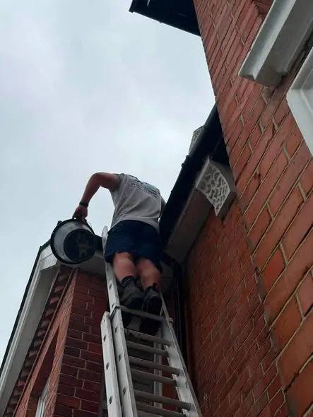 Clearing a gutter by hand, FR Roofing Solutions