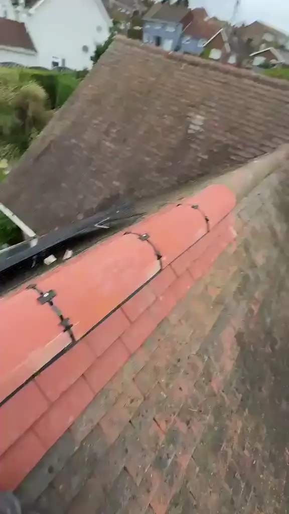 Red ridge tiles fixed along a pitched roof, FR Roofing Solutions